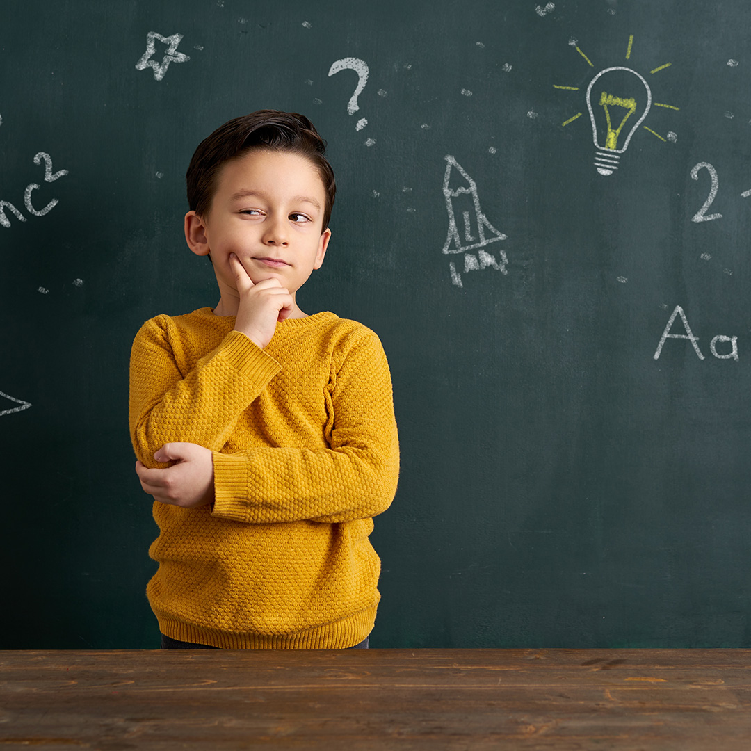Child thinking with blackboard of ideas in background