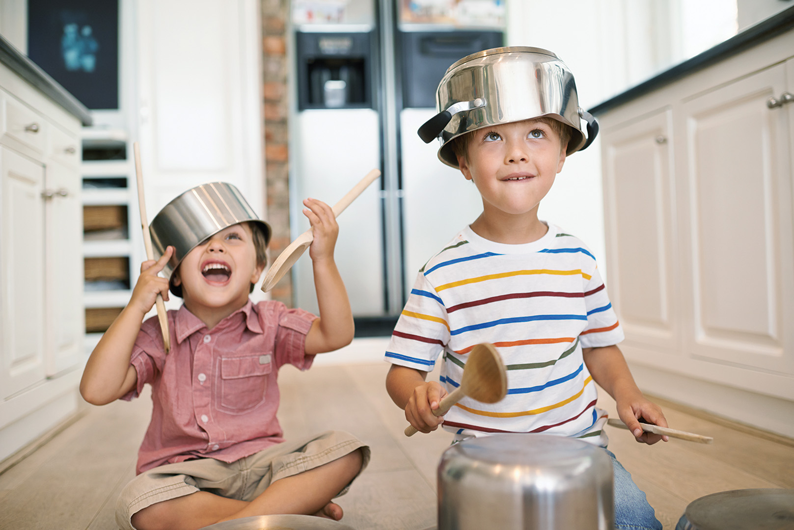Raising boys means prioritising play. Two young boys playing with kitchen utensils and pots.