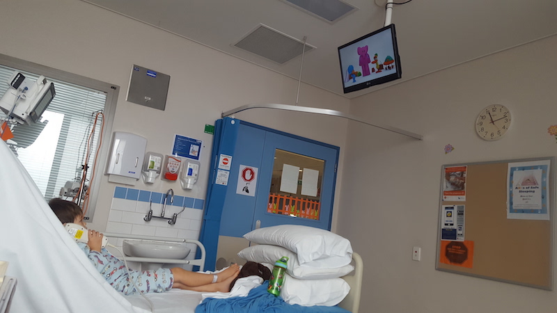 Toddler in hospital bed watching TV