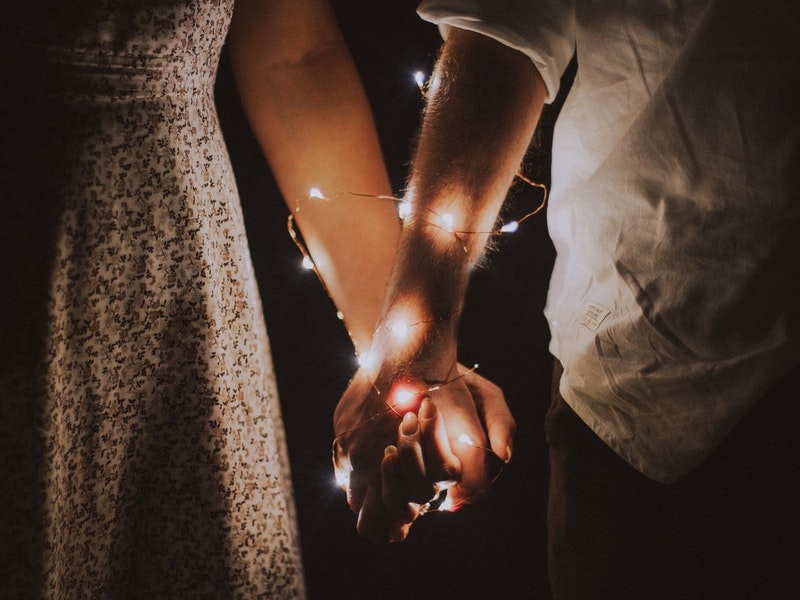 Holding hands with entwined fairy lights