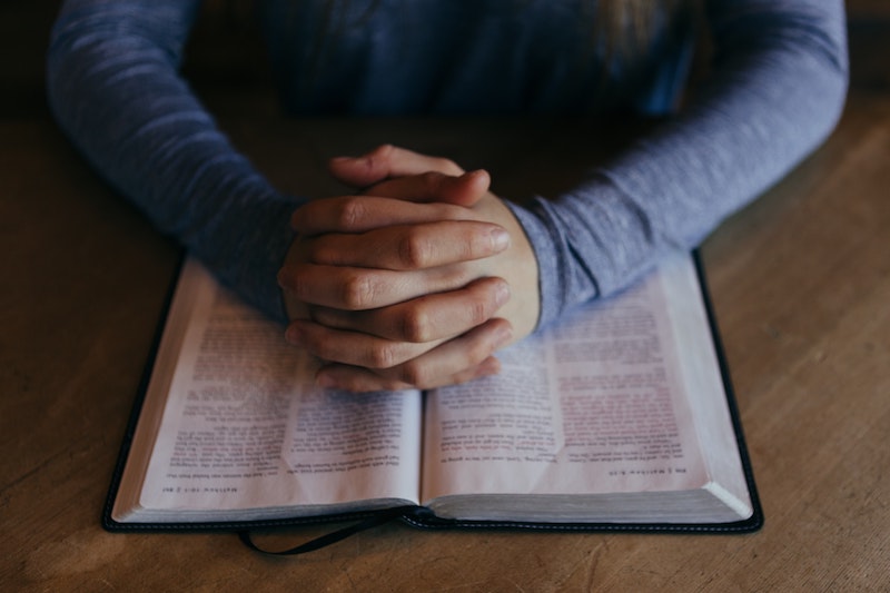 Hands resting on Bible in prayer pose