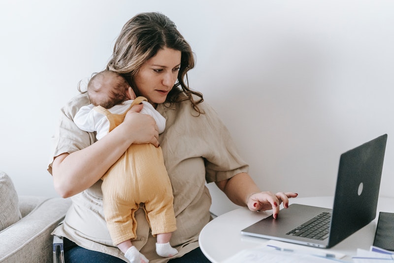 Mum holding baby and on laptop