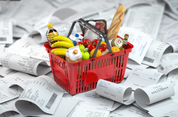 Toy shopping basket with foods on a pile of receipt.
