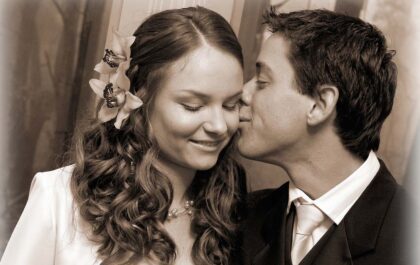 Wedding photo of groom kissing bride on cheek