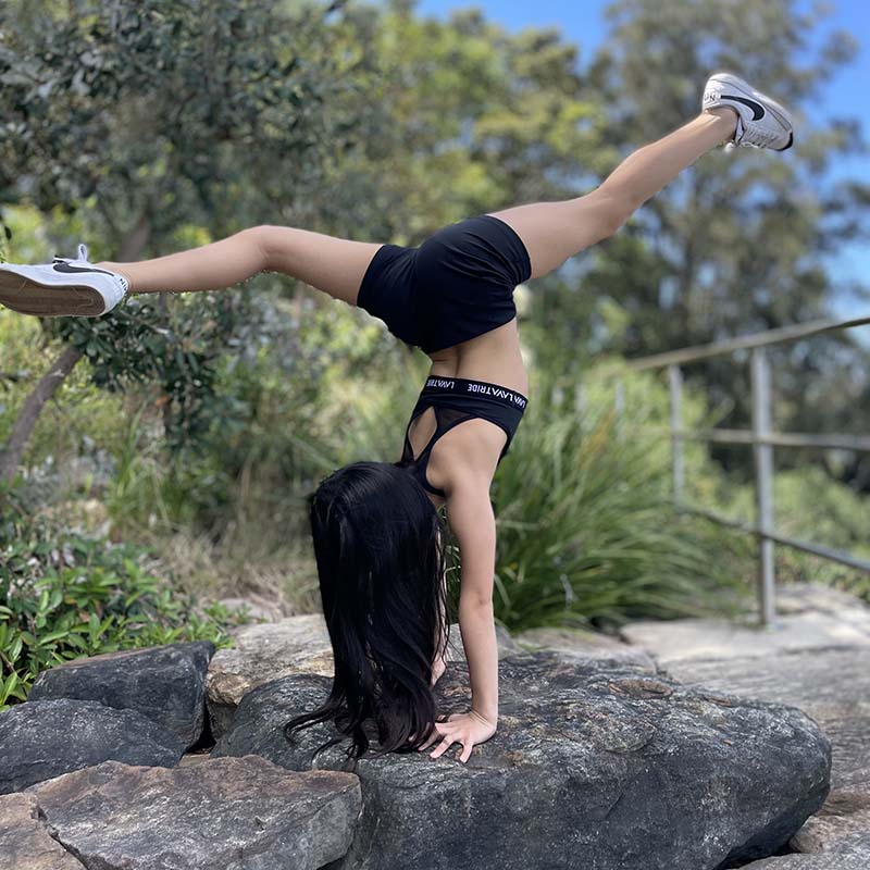 Girl doing a hand stand on a rock