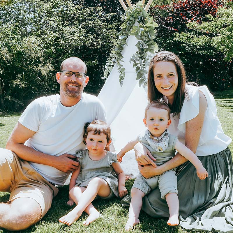 Dad, mum and two kids sitting in front of a teepee in the garden