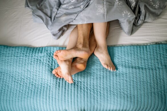 Feet of a couple in bed, sticking out from under the sheets