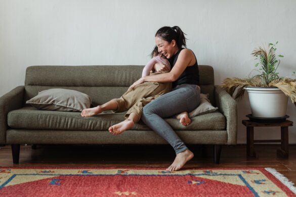 Mum sitting on a couch happily hugging her preschool-aged daughter