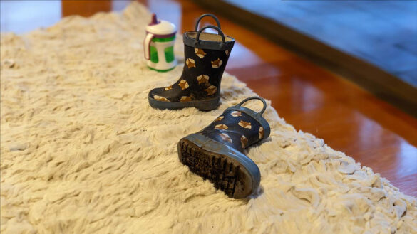 Dirty child's gumboots with mud dropping onto the white Double rug they're resting on
