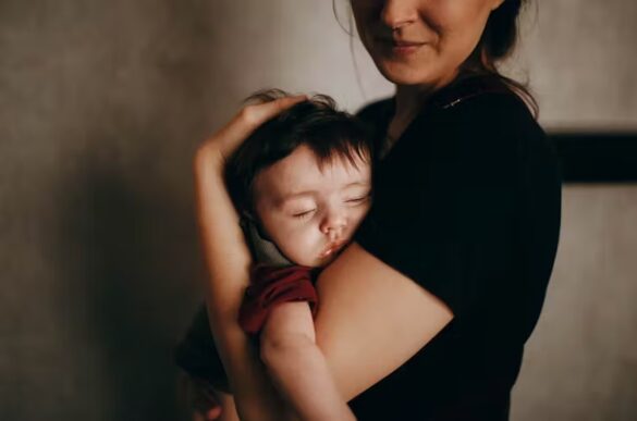 Woman carrying a sleeping toddler.