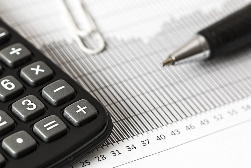 Close-up of a corner of a calculator, pen and a piece of paper with graphs printed on it