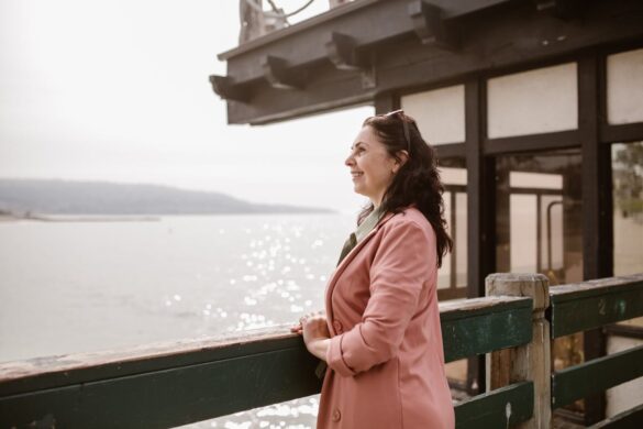 Smiling woman leaning against a rail, staring out into the ocean