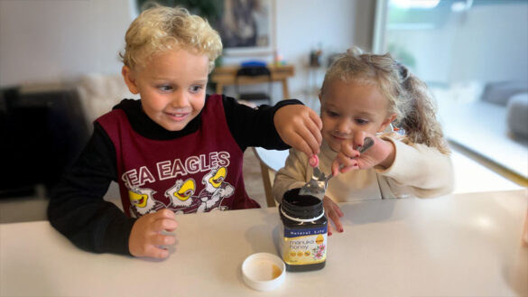 Two children spooning out honey from a honey jar
